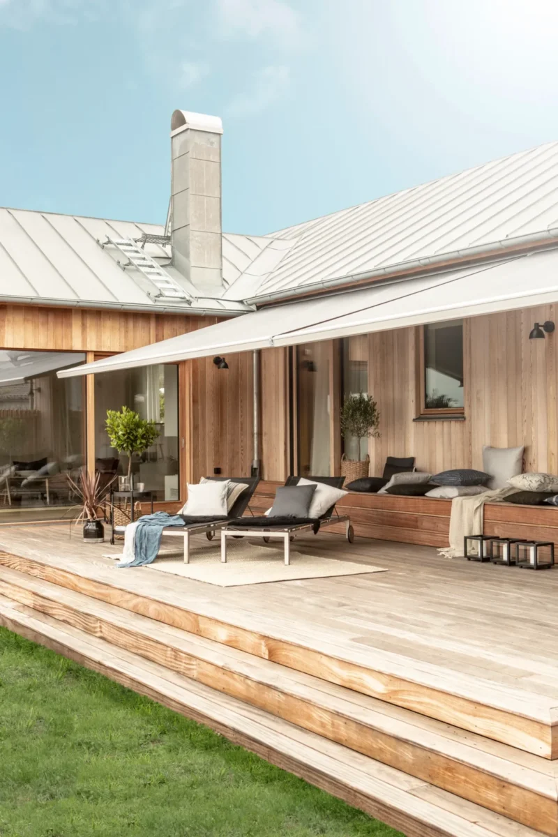Terrassmarkis utfälld över trädäcket på en villa med träfasad