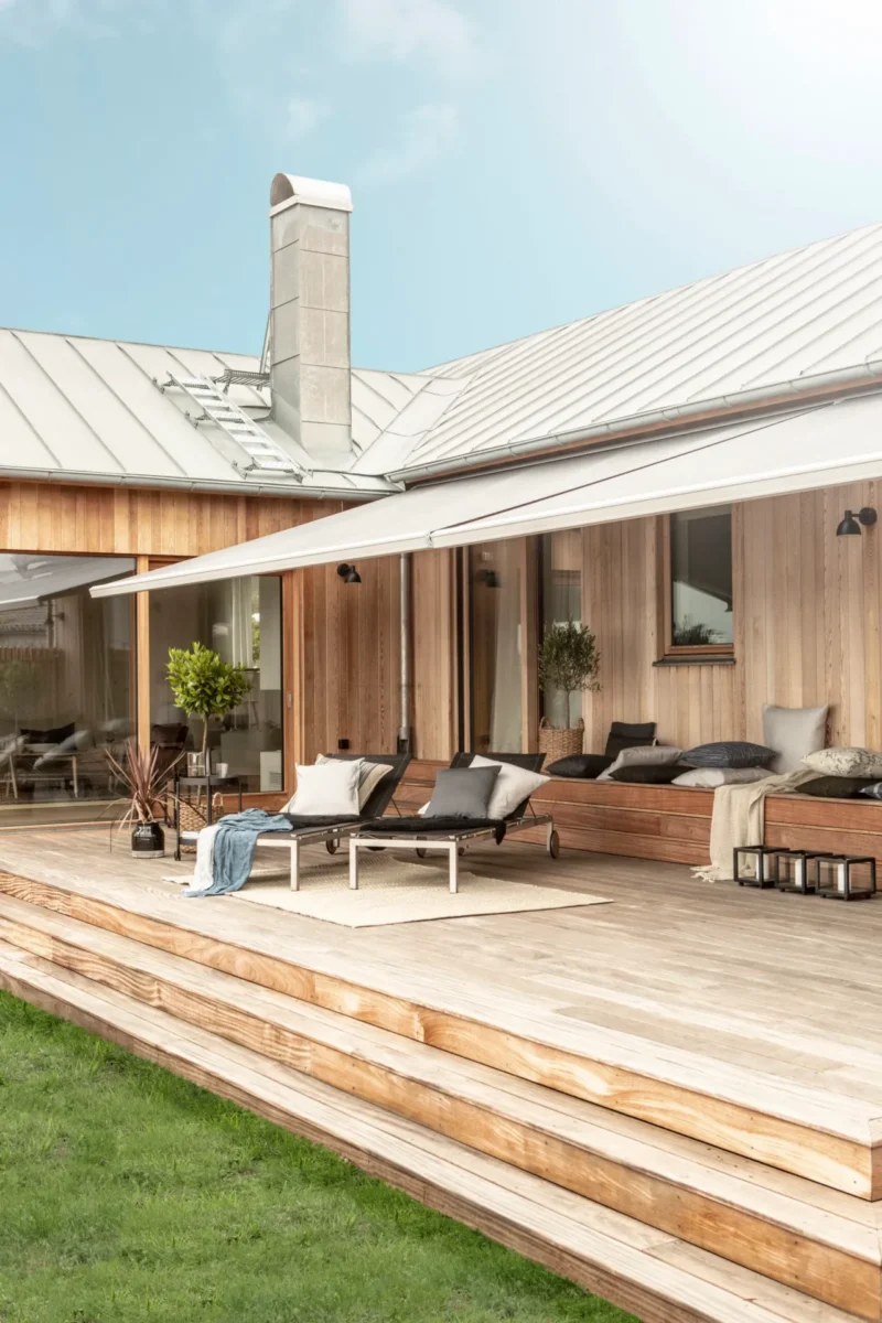 Terrassmarkis utfälld över trädäcket på en villa med träfasad