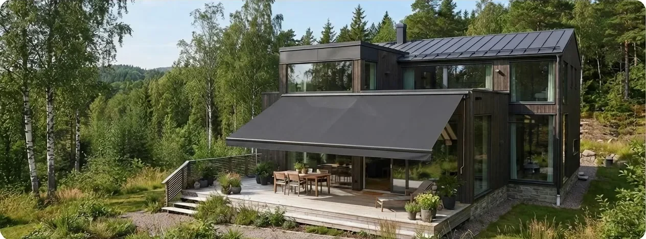 Mörk villa i skogsmiljö med en stor terrassmarkis utfälld över uteplatsen