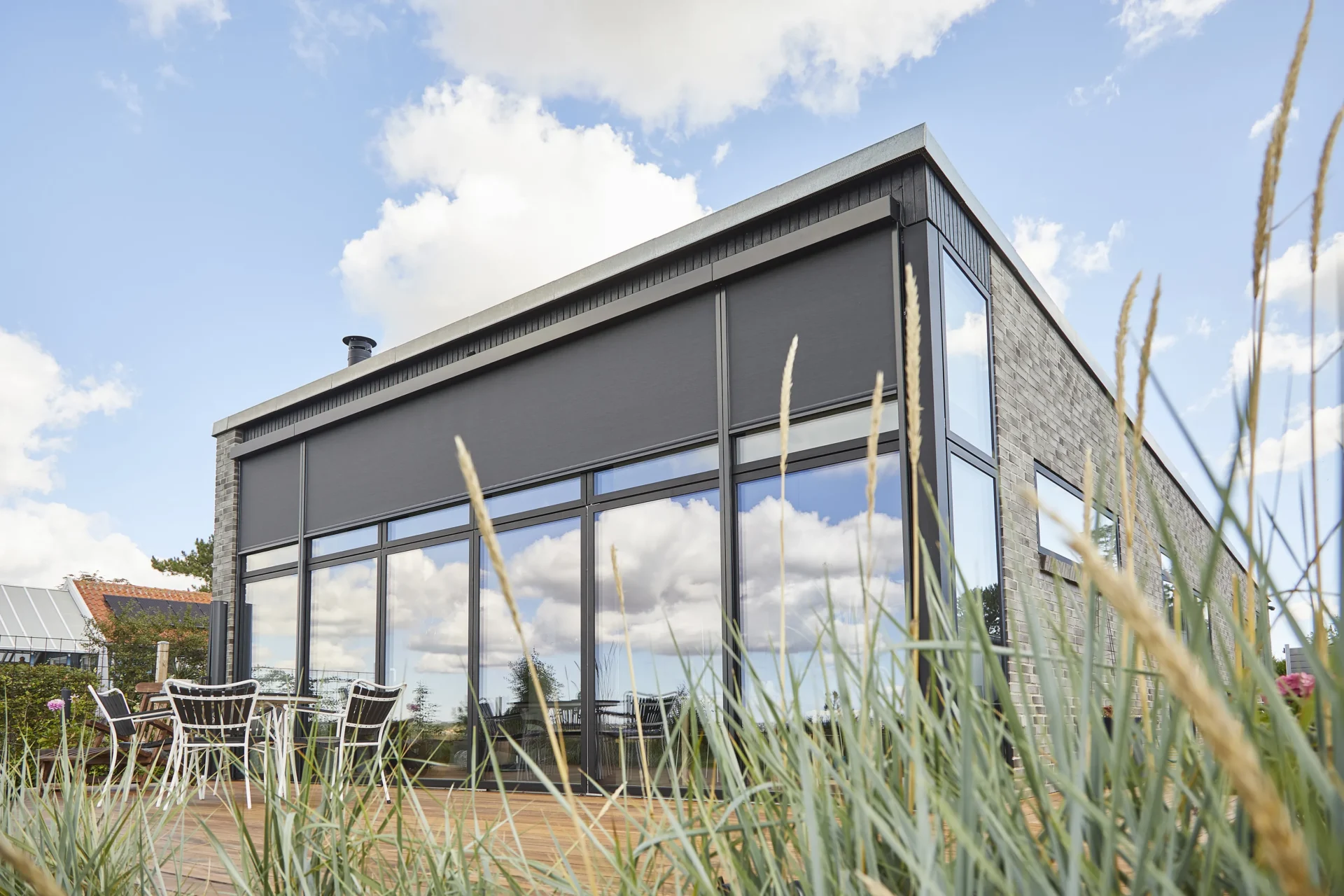 Modern villa med mörka zipscreens nedfällda över stora glaspartier