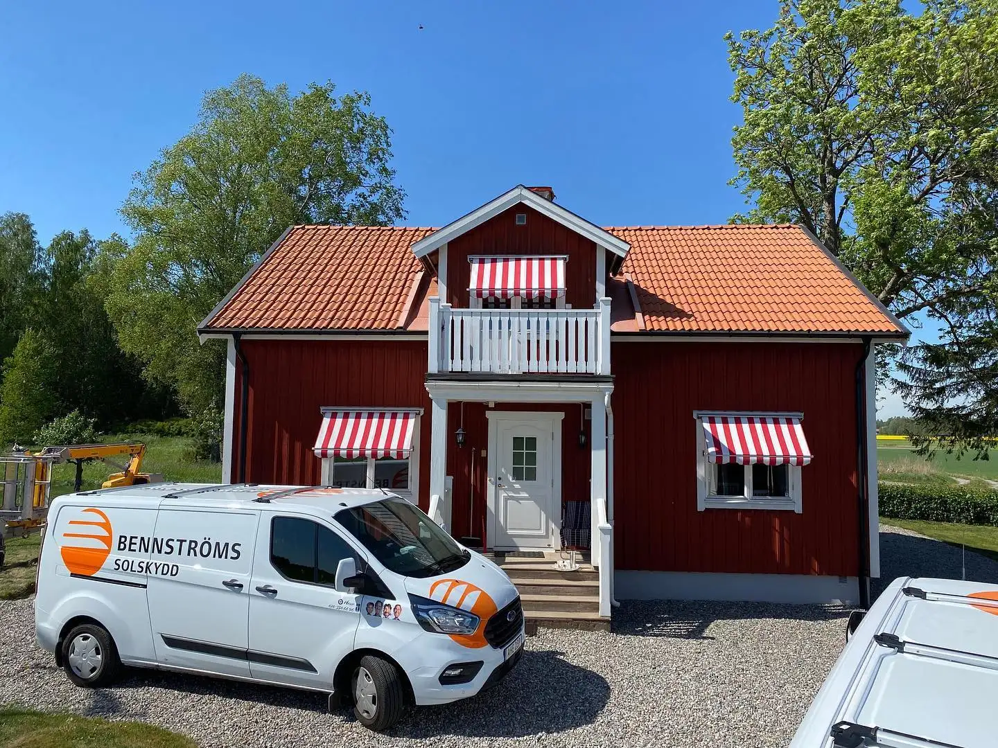 Bennströms servicebil framför ett rött trähus med röd- och vitrandiga fönstermarkiser