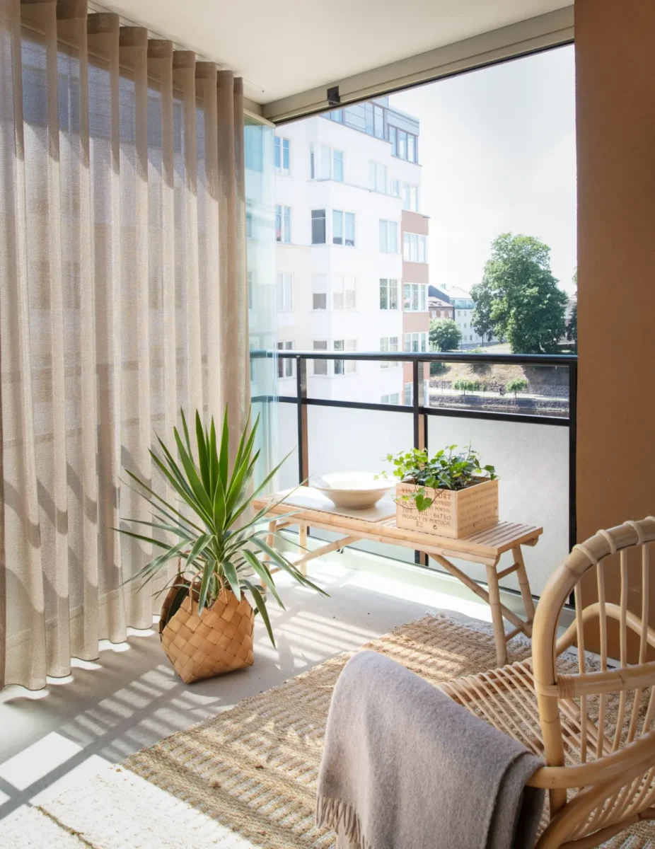 Skira beige gardiner på en inglasad balkong med rottingmöbler