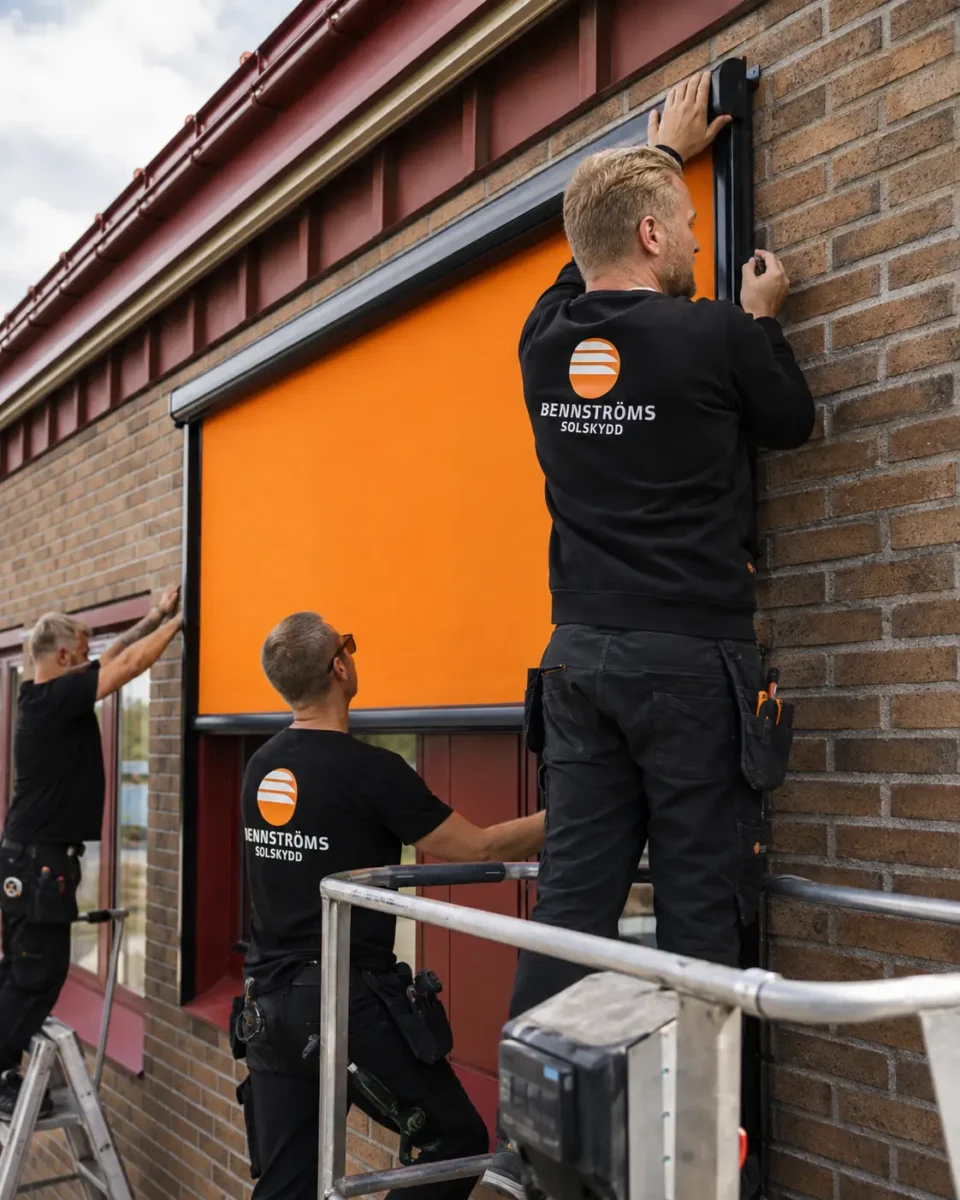 Tre montörer från Bennströms monterar en orange zipscreen på Rönnbyskolan