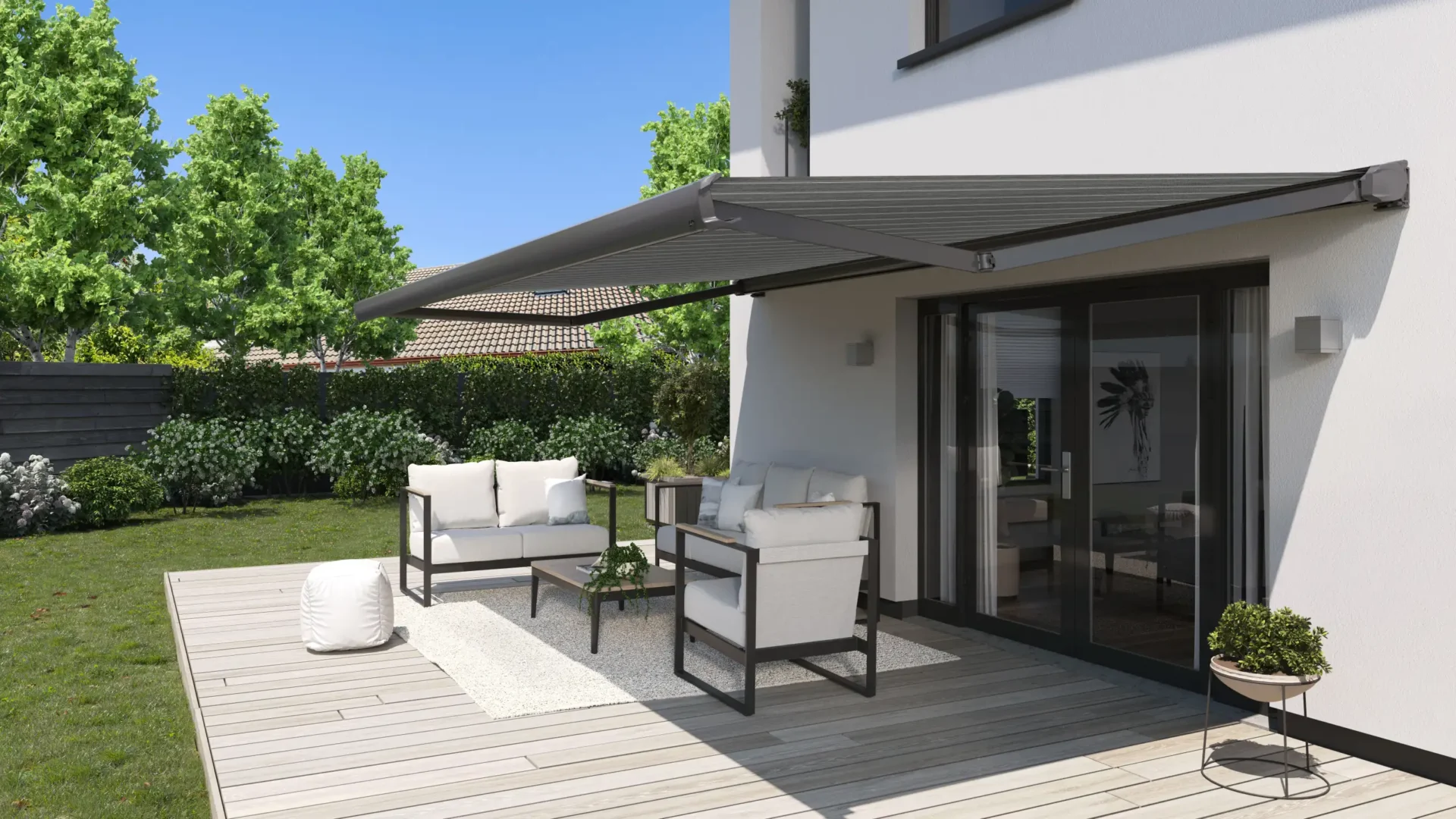Mörkgrå terrassmarkis över ett trädäck med vita loungemöbler vid en vit villa