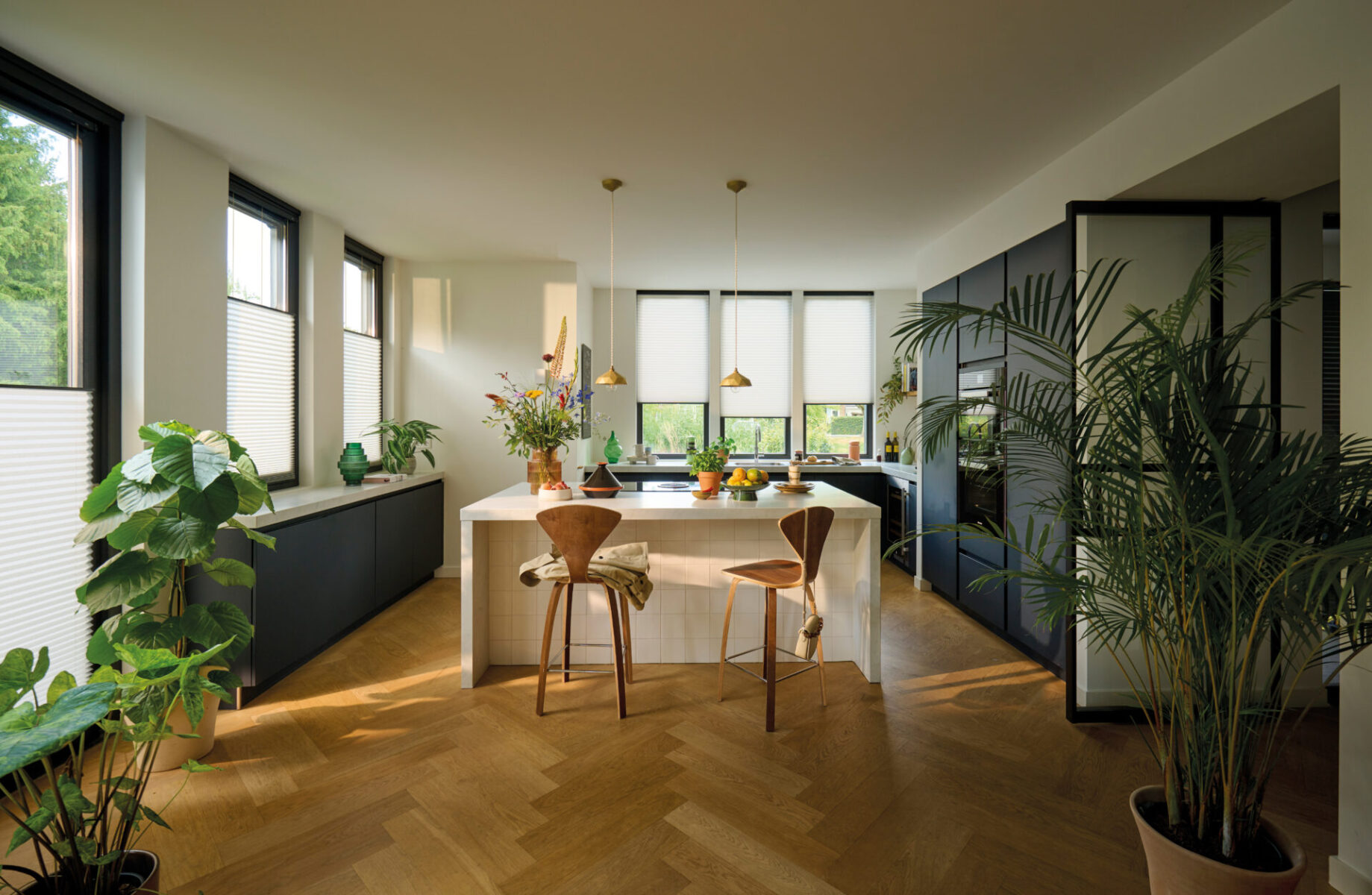 Öppen planlösning med kök och matplats där vita plisségardiner sitter i fönstren
